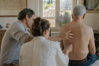 Student and supervisor concentrate on osteopathic palpation in a warm, sunlit Provence clinic, with Mediterranean decor and an authentic, learning-focused atmosphere.